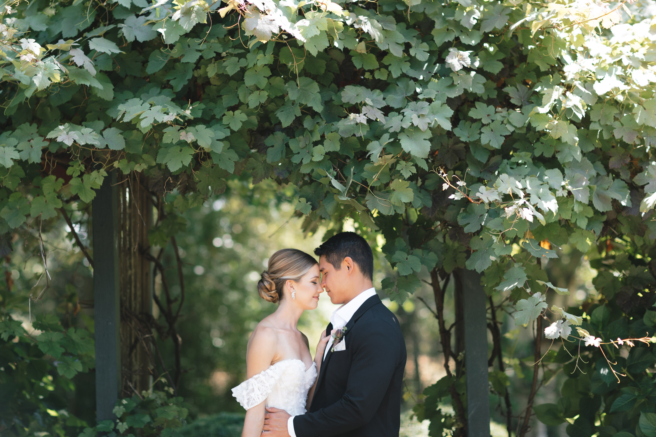 Portrait of bride and groom underneath a trellis at Froggsong Gardens in Vashon Island.