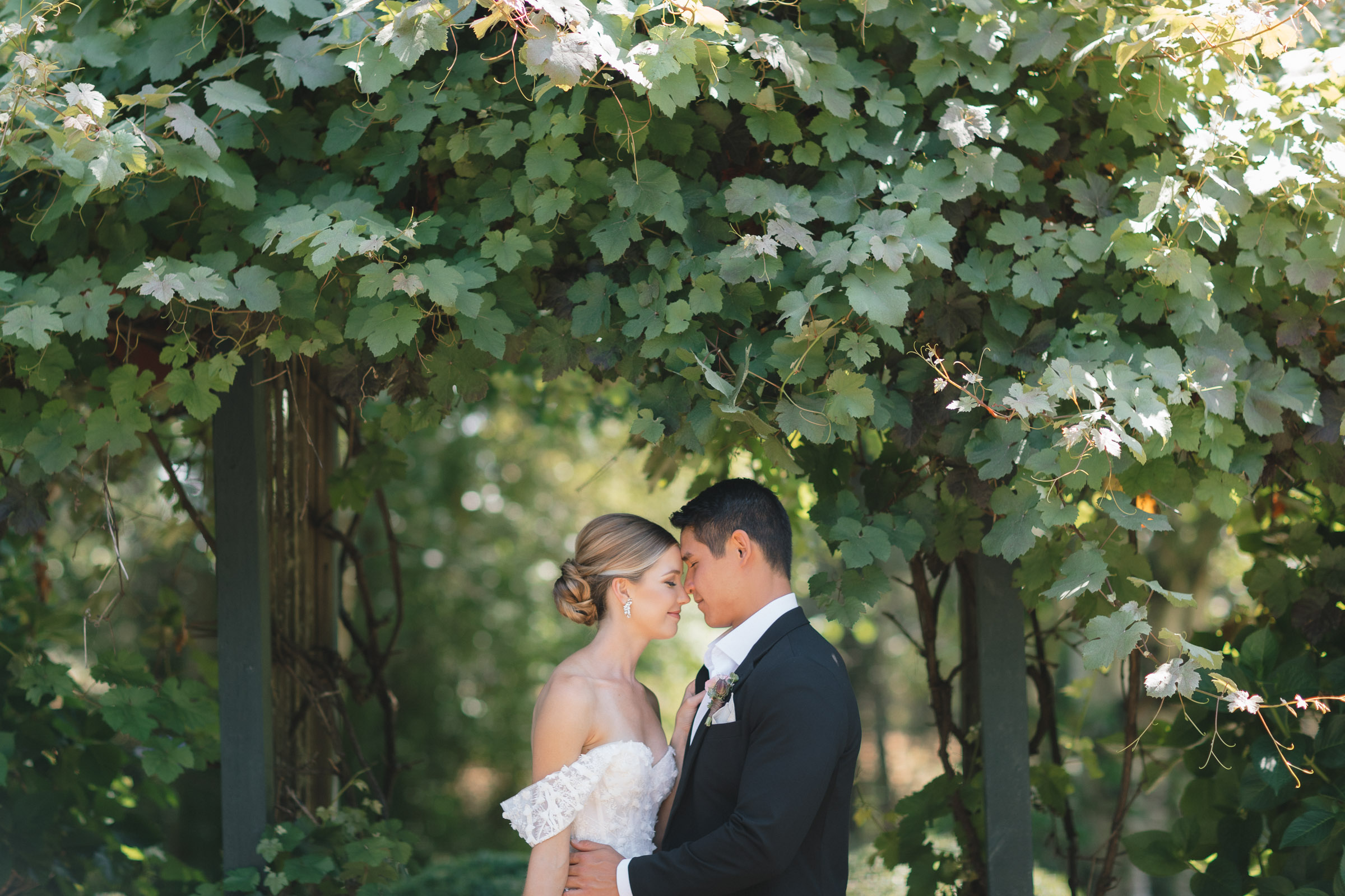 Portrait of bride and groom underneath a trellis at Froggsong Gardens in Vashon Island.
