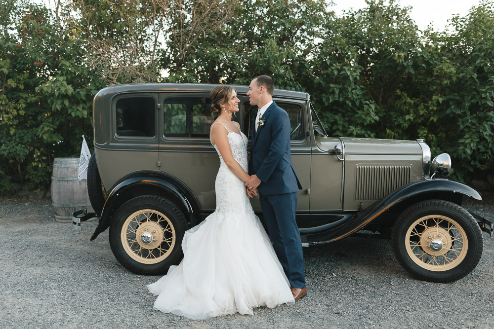 Bride and groom standing in front of a classic car at their Chateau Lill wedding in Woodinville.