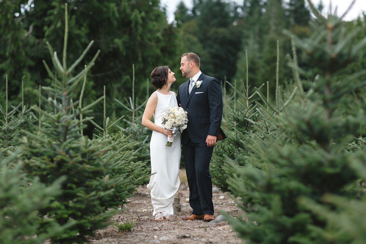 Couple standing in grove of trees at Trinity Tree Farm in Issaquah.