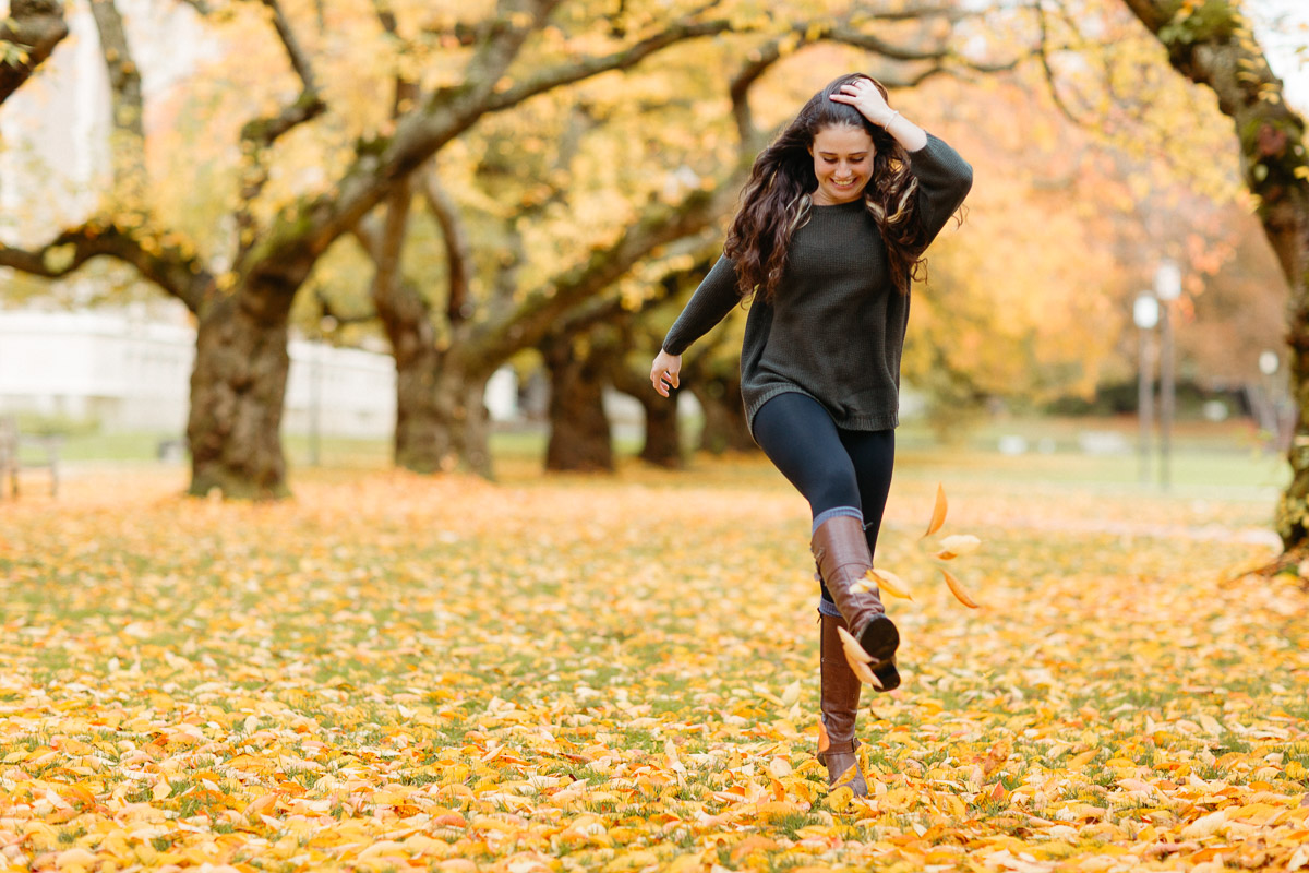 Woman joyfully walking in colorful autumn University of Washington campus.