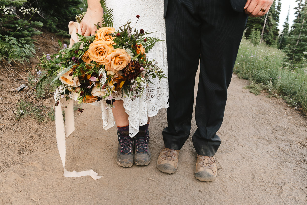 Bride in lace dress and groom with hiking boots, outdoors