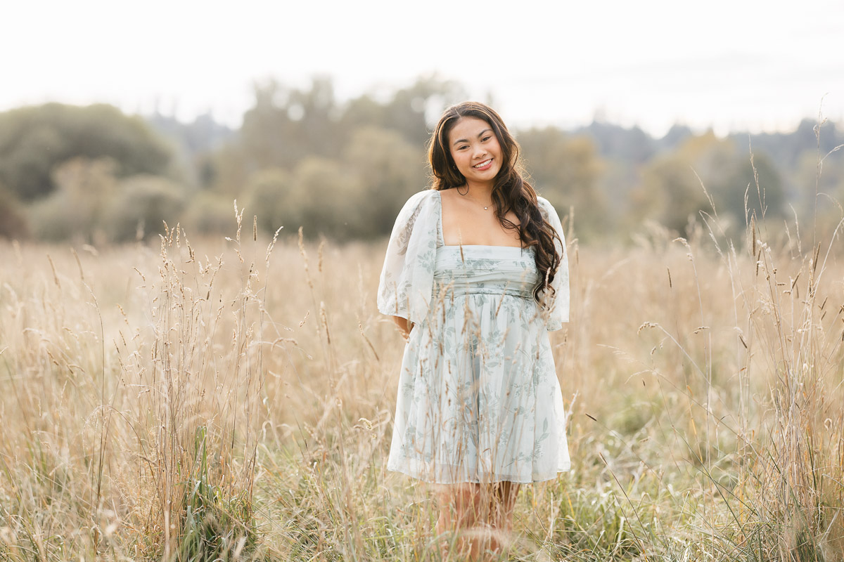 High school senior girl smiling in field wearing floral dress