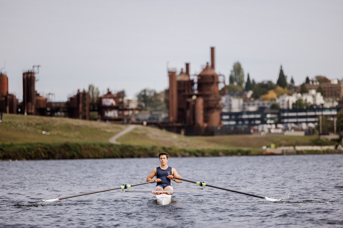 High school senior rowing on Lake Union with industrial backdrop of Gasworks Park.