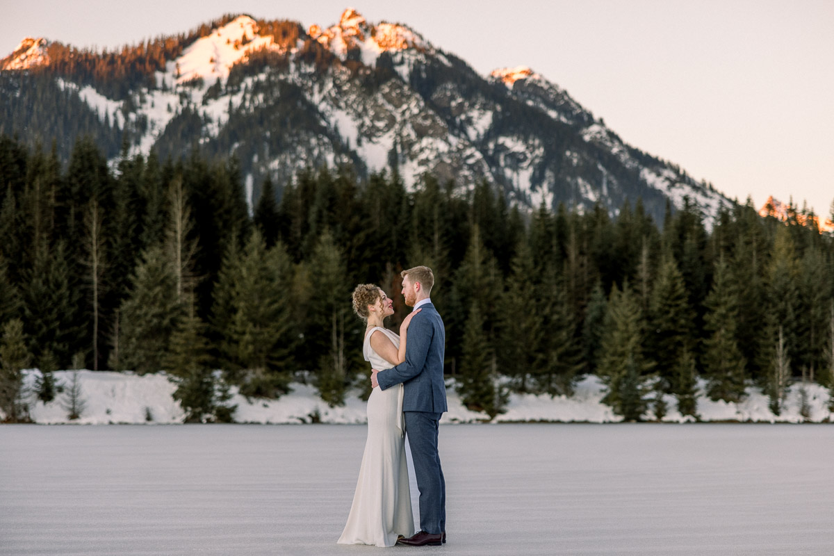 couple standing in front of mountain terrain at Gold Creek Pond in Washington State.