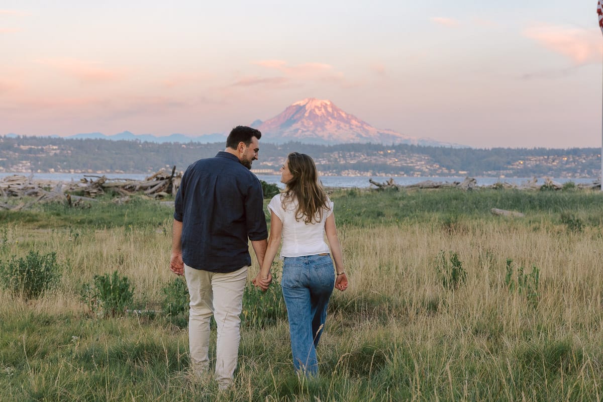 Couple walking on the beach at Point Robinson Park on Vashon with Mount Rainier Visible in the distance