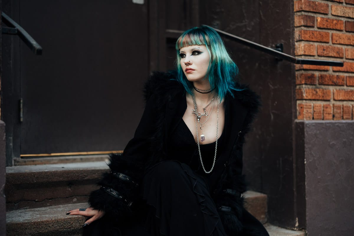 Young high school senior girl dressed in goth themed outfit posing at a seattle street for her senior photos