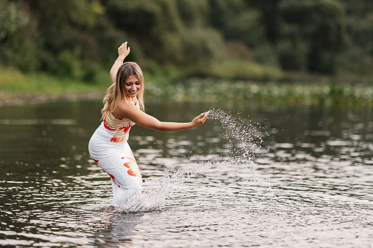 Sammamish high schol senior splashing water in while standing in Lake Sammamish