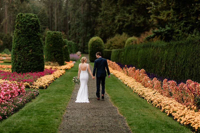 Bride and groom walking in garden holding hands